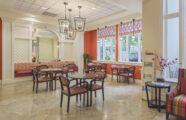 A spacious lobby with comfortable chairs and tables positioned near windows, creating a welcoming atmosphere at The Gardens at Town Square.