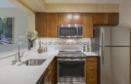 apartment kitchen with mahogany wood finishes and silver fixtures and appliances.