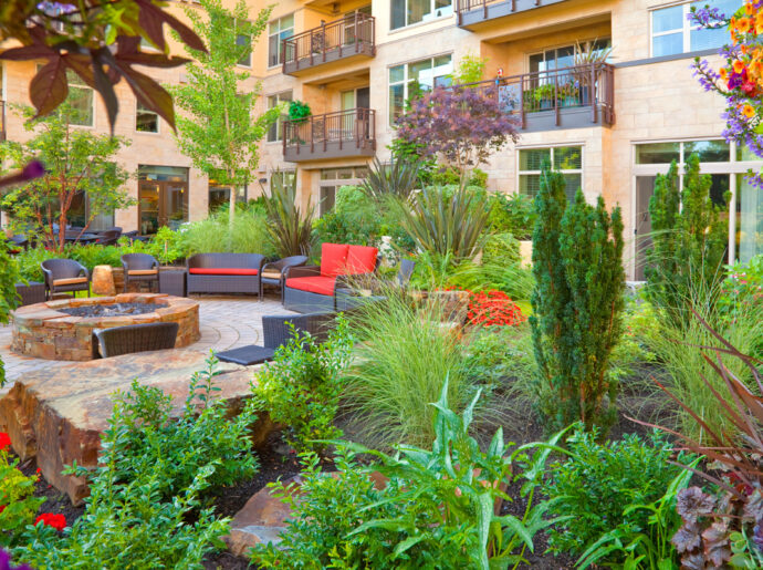 Inviting courtyard garden at the Aljoya Mercer Island retirement community, featuring lush landscaping, comfortable seating, water feature, and fire pit for seniors to relax and socialize outdoors in Mercer Island.