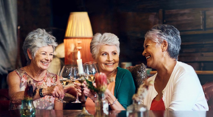 3 older women toasting with wine at a holiday party