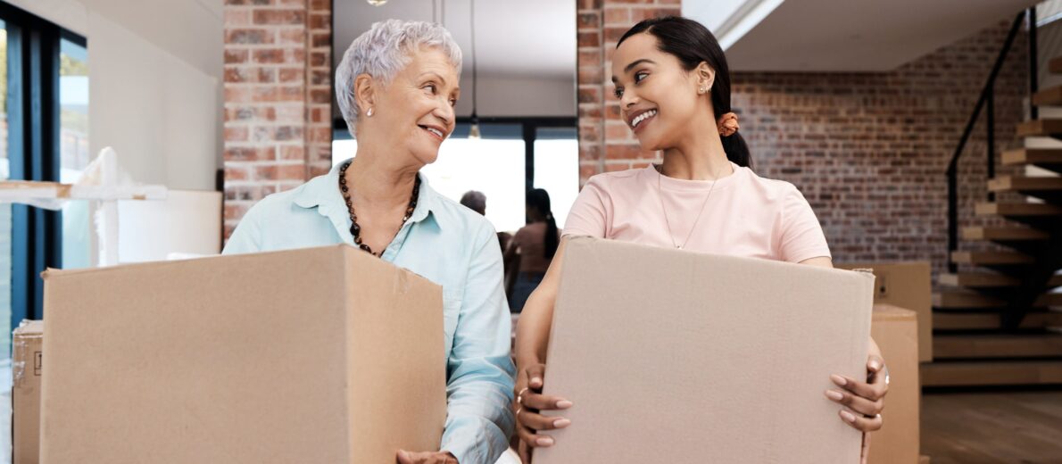 Grandma and her granddaughter in a living room holding moving boxes and working on downsizing to a retirement community