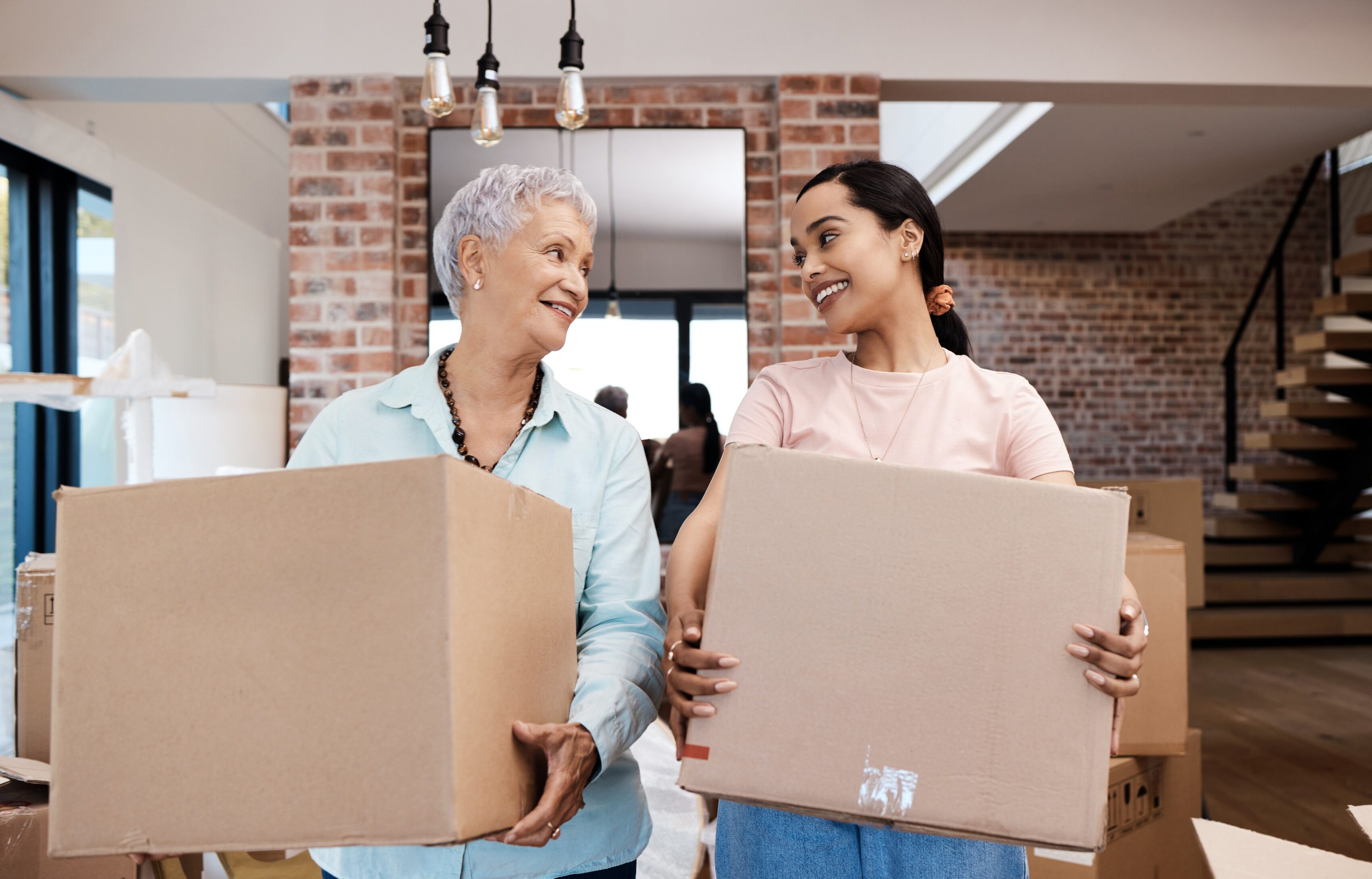 Grandma and her granddaughter in a living room holding moving boxes and working on downsizing to a retirement community