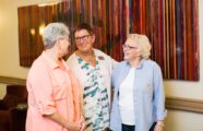 the executive director and two residents talking in front of colorful wall art