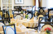 Elegant dining room view of white linen on tables with complete table setting