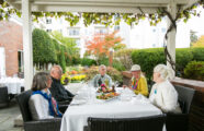 Friendly neighbors in a group setting enjoying lunch outside in courtyard of Seattle retirement community