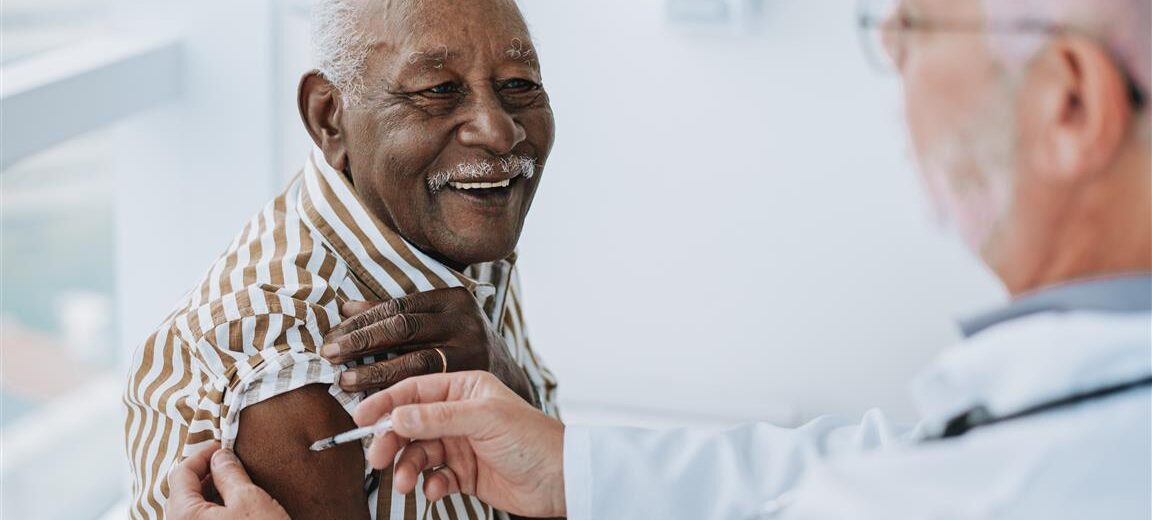 Senior gentleman getting vaccinated by pharmacist.