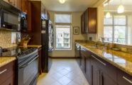 Stylish designer kitchen in an apartment at the Aljoya Mercer Island retirement community in Mercer Island, featuring black appliances and cherry wood cabinets.