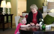 Laughing grandma and granddaughter playing with puzzle