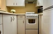 Apartment kitchen with refrigerator, stove-top, oven and white cabinets.