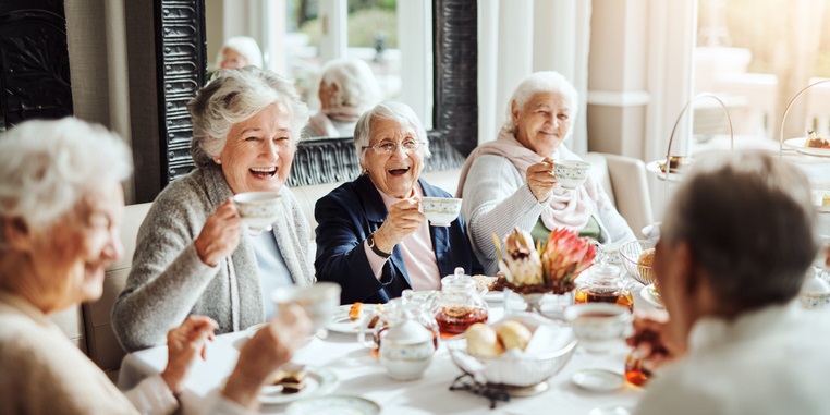 Smiling older women enjoying a tea party together