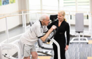 senior man enjoying fitness class with personal trainer in gym of Seattle retirement community